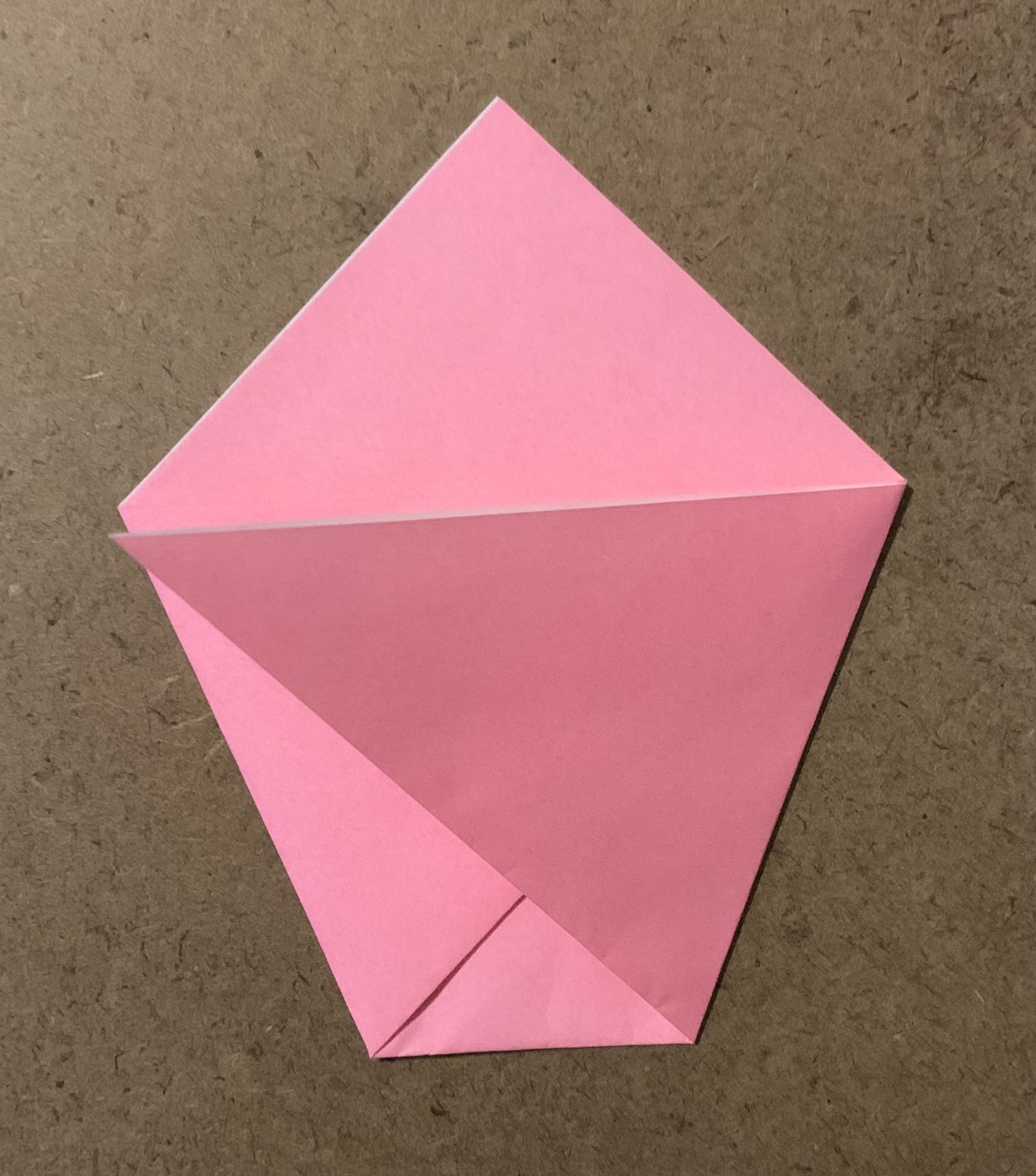 origami paper with right point folded across the top over the folded left point